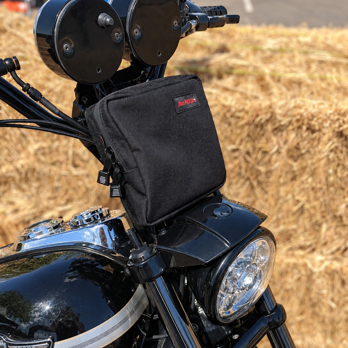 Black Moto Pockets Mini T-Bar motorcycle handlebar bag mounted on a Harley-Davidson with tall handlebar risers, showing its compact fit above the headlight.