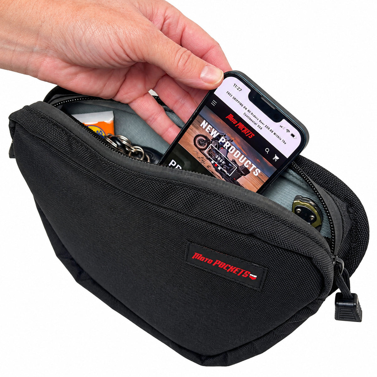 Moto Pockets OG T-Bar motorcycle handlebar bag open with a smartphone being placed inside, showing storage for keys and everyday riding essentials.